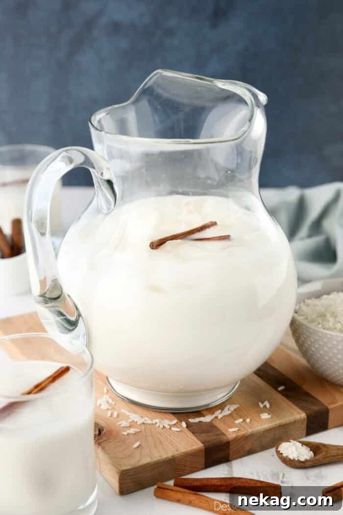 Homemade Horchata Made Easy 8 A large pitcher of Mexican horchata, garnished with ice and cinnamon sticks, ready for serving.