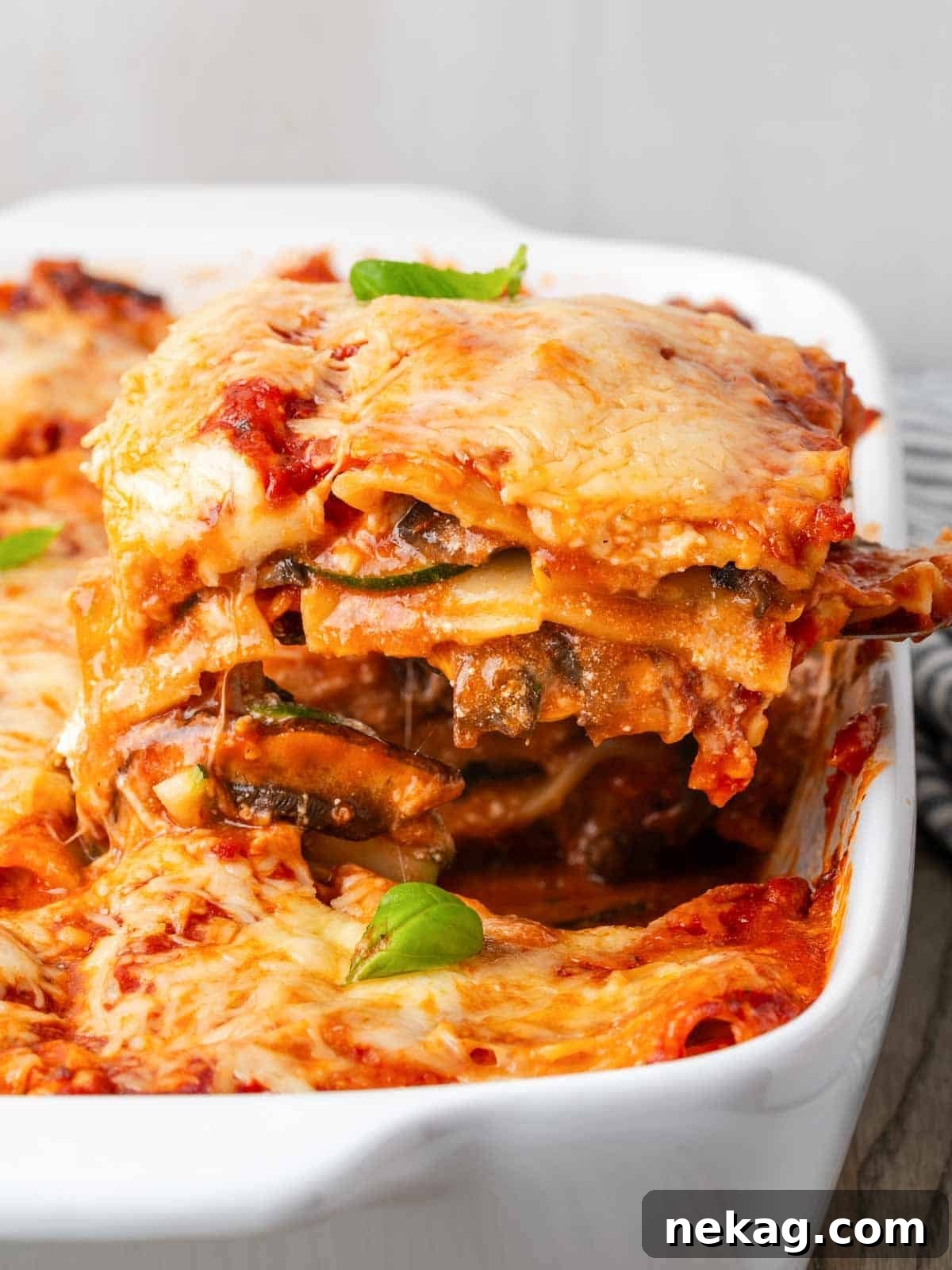Seasonal Vegetable Lasagna 2 A perfectly sliced piece of vegetable lasagna, showcasing layers of pasta, rich sauce, vibrant vegetables, and melted cheese, served on a white dish.