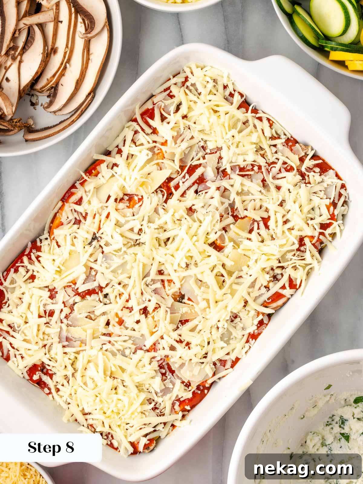 Seasonal Vegetable Lasagna 12 A fully assembled vegetable lasagna, topped with a generous layer of mozzarella and parmesan cheese, ready for baking.