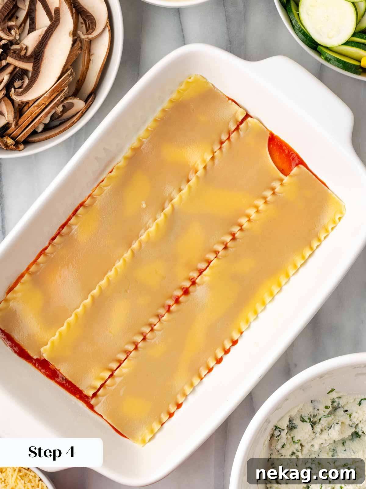 Seasonal Vegetable Lasagna 6 Placing overlapping lasagna noodles into a baking dish already coated with a thin layer of tomato sauce.