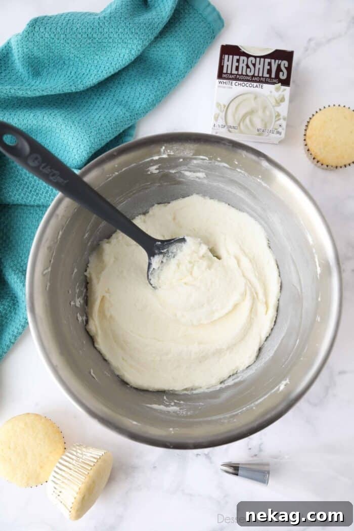 Delicious Pudding Buttercream Frosting Recipe 3 Bowl of pudding frosting with a spatula inserted and a box of Hershey's white chocolate instant pudding mix.