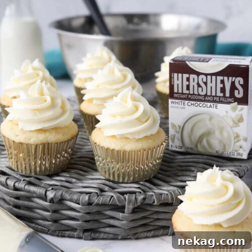 Cupcakes topped with white chocolate pudding buttercream frosting made with instant pudding mix.