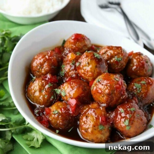 Sweet Fire Meatballs served over rice, garnished with fresh herbs.