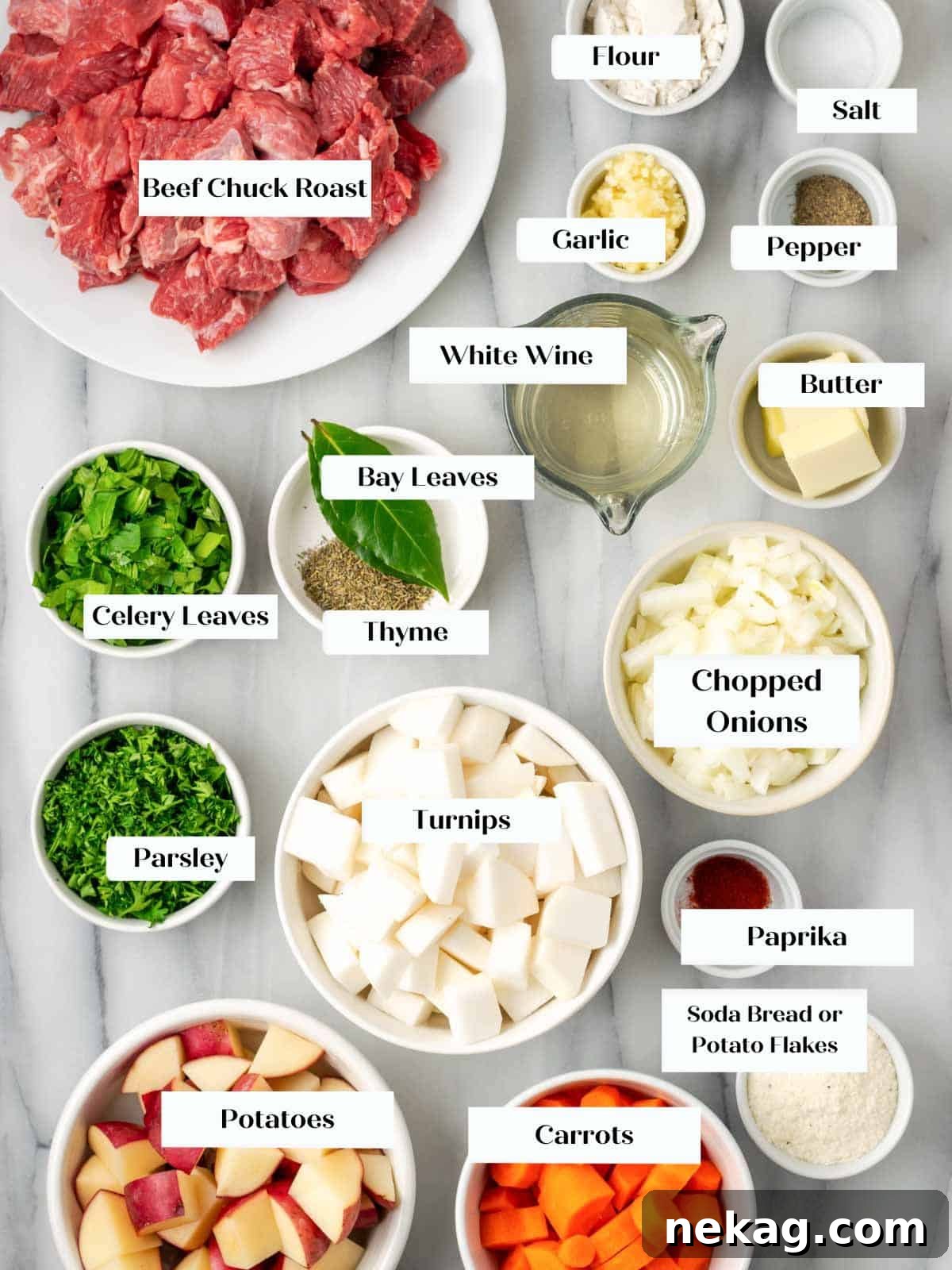 Assortment of fresh ingredients for beef stew laid out on a marble surface.
