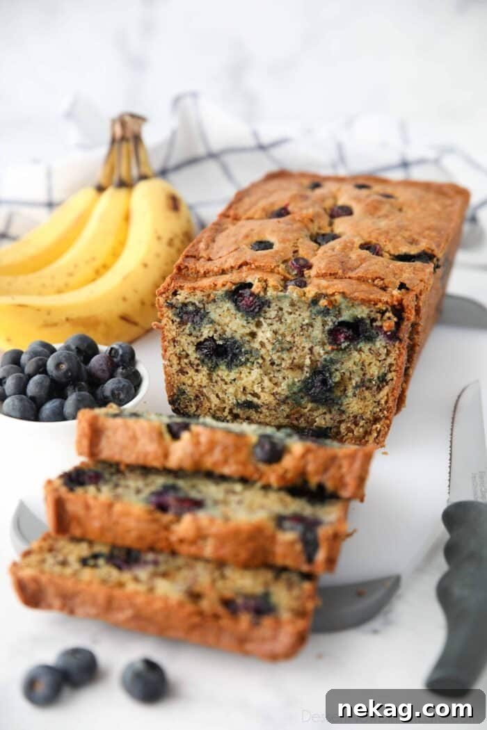 Berry-Kissed Banana Bread 3 A loaf of blueberry banana bread with sour cream, cut open to reveal the soft, moist interior dotted with blueberries.