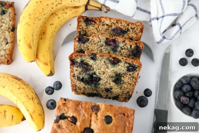 Berry-Kissed Banana Bread 7 Slices of sour cream banana blueberry bread neatly arranged on a wooden cutting board, showcasing the vibrant blueberries.