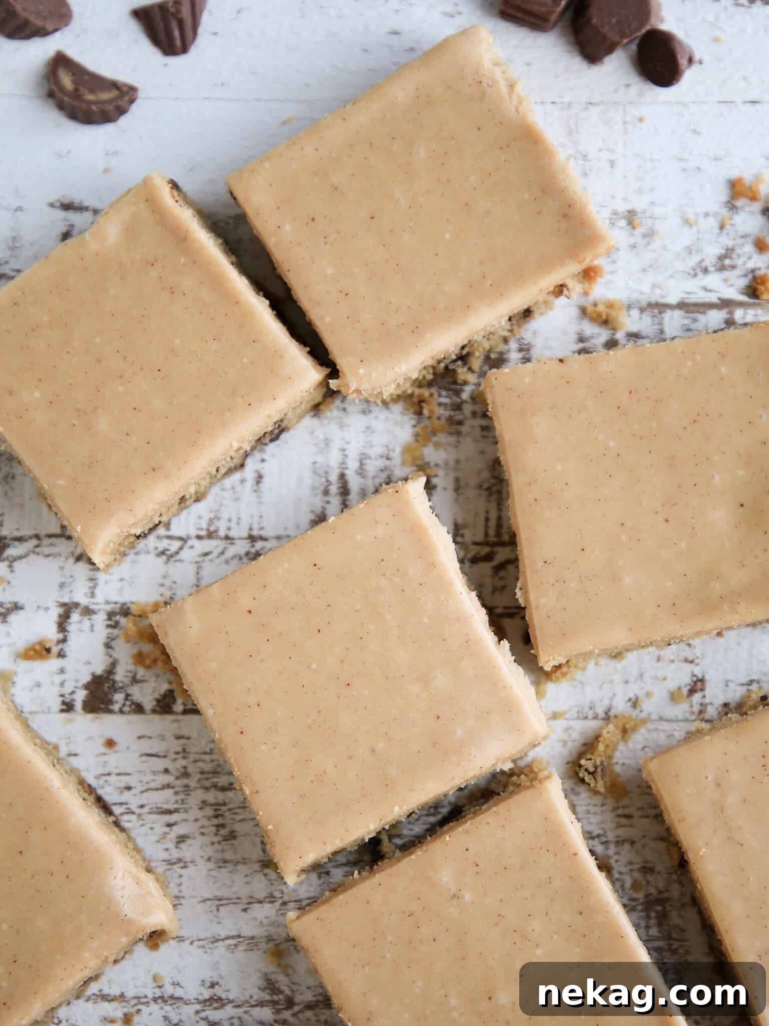 Ultimate Reeses Peanut Butter Blondies 4 Several Reese's Peanut Butter Blondies, neatly sliced, arranged on a rustic wooden surface, highlighting their gooey centers and generous frosting.