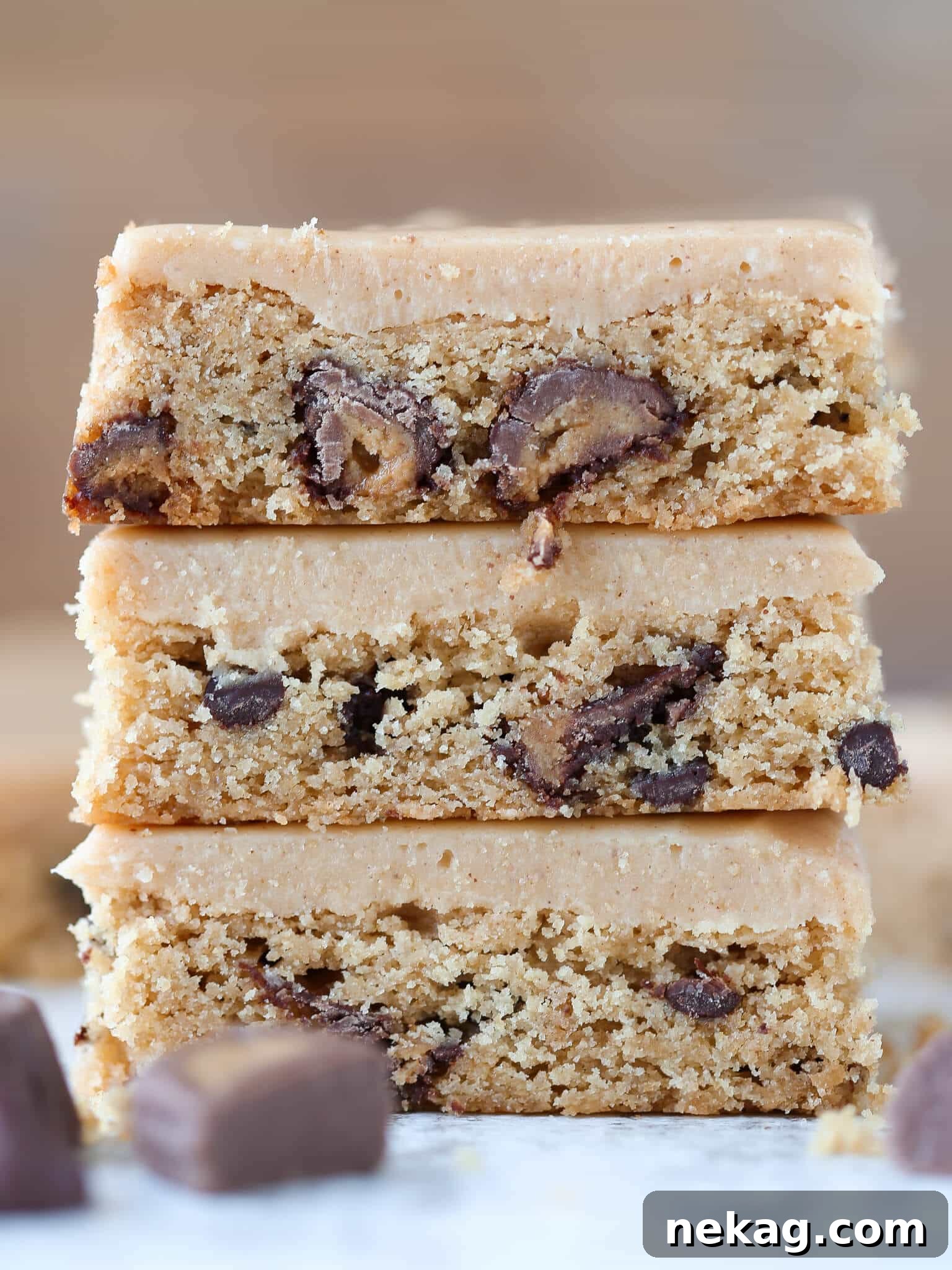 Ultimate Reeses Peanut Butter Blondies 6 A tall stack of Reese's Peanut Butter Blondies heavily frosted with creamy peanut butter icing, ready to be enjoyed.