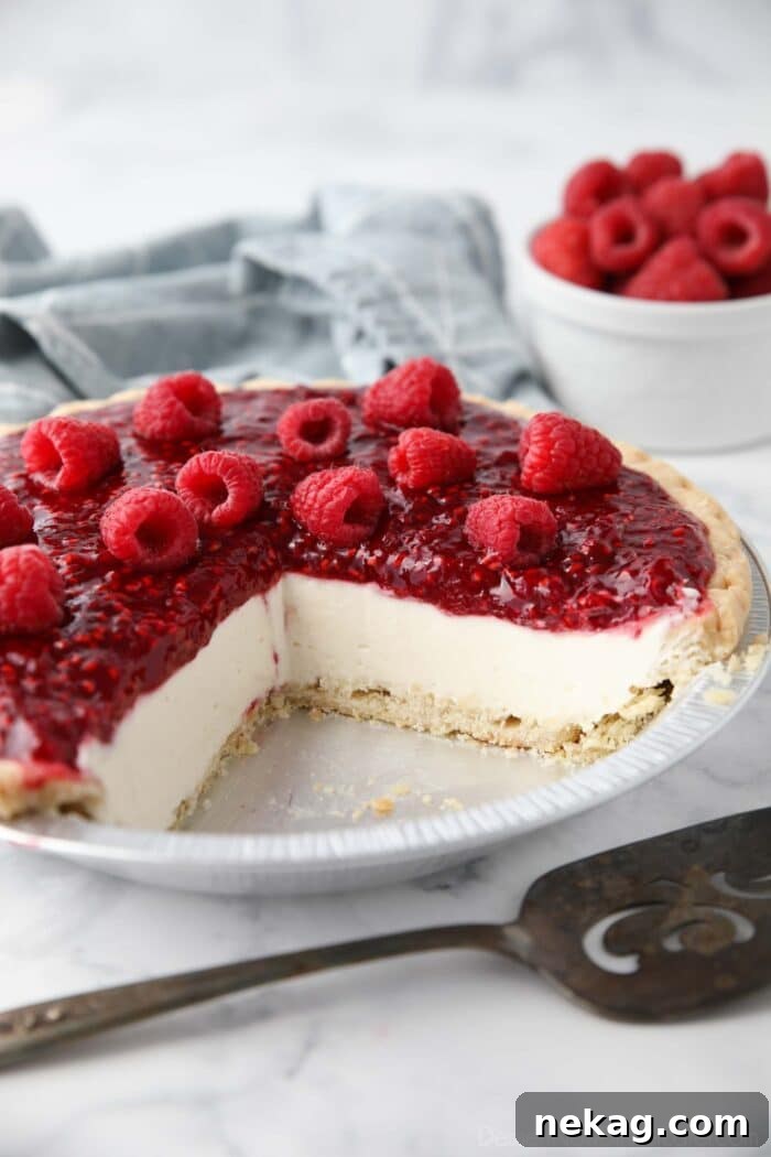 Slices removed from pie pan to show the inside of Raspberry Cream Pie with a pastry crust, whipped cream cheese filling and raspberry topping.