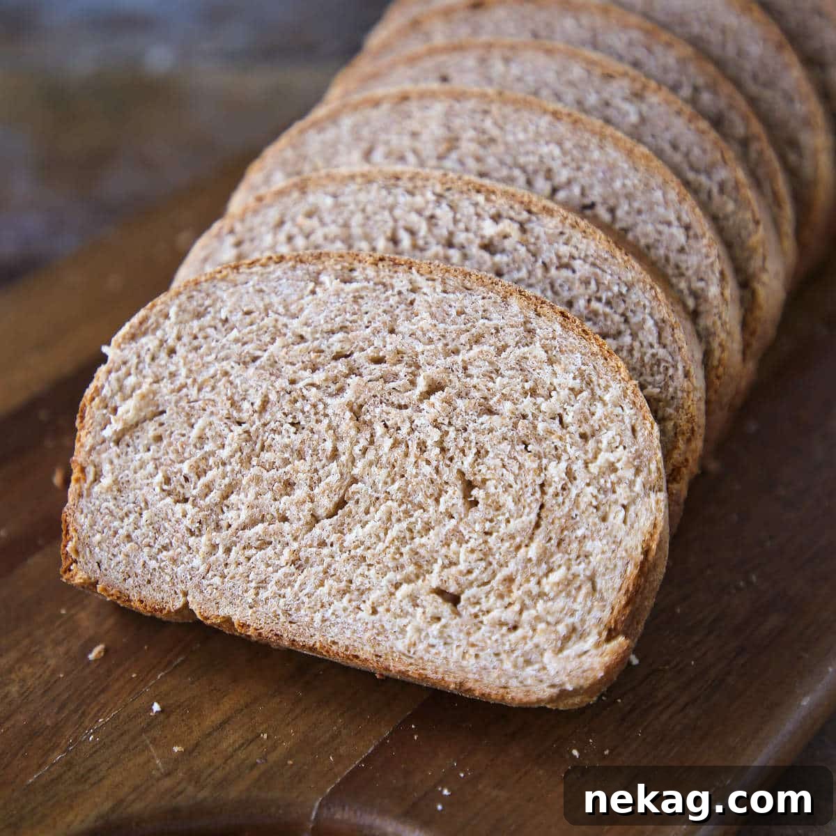 Whole Wheat Breadmaking 4 Sliced whole wheat bread on a rustic wooden board, showing its beautiful crumb.