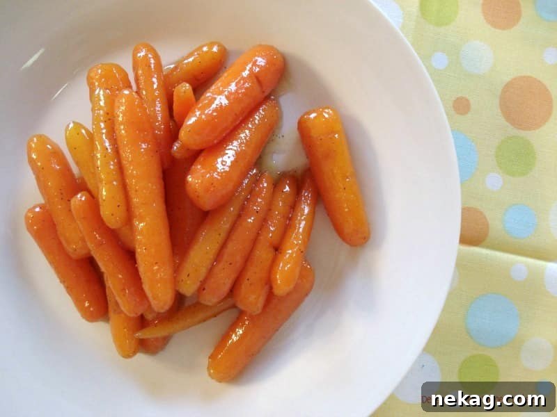 Close-up of Honey Glazed Carrots simmering in a skillet, showcasing the glossy glaze and vibrant orange color.
