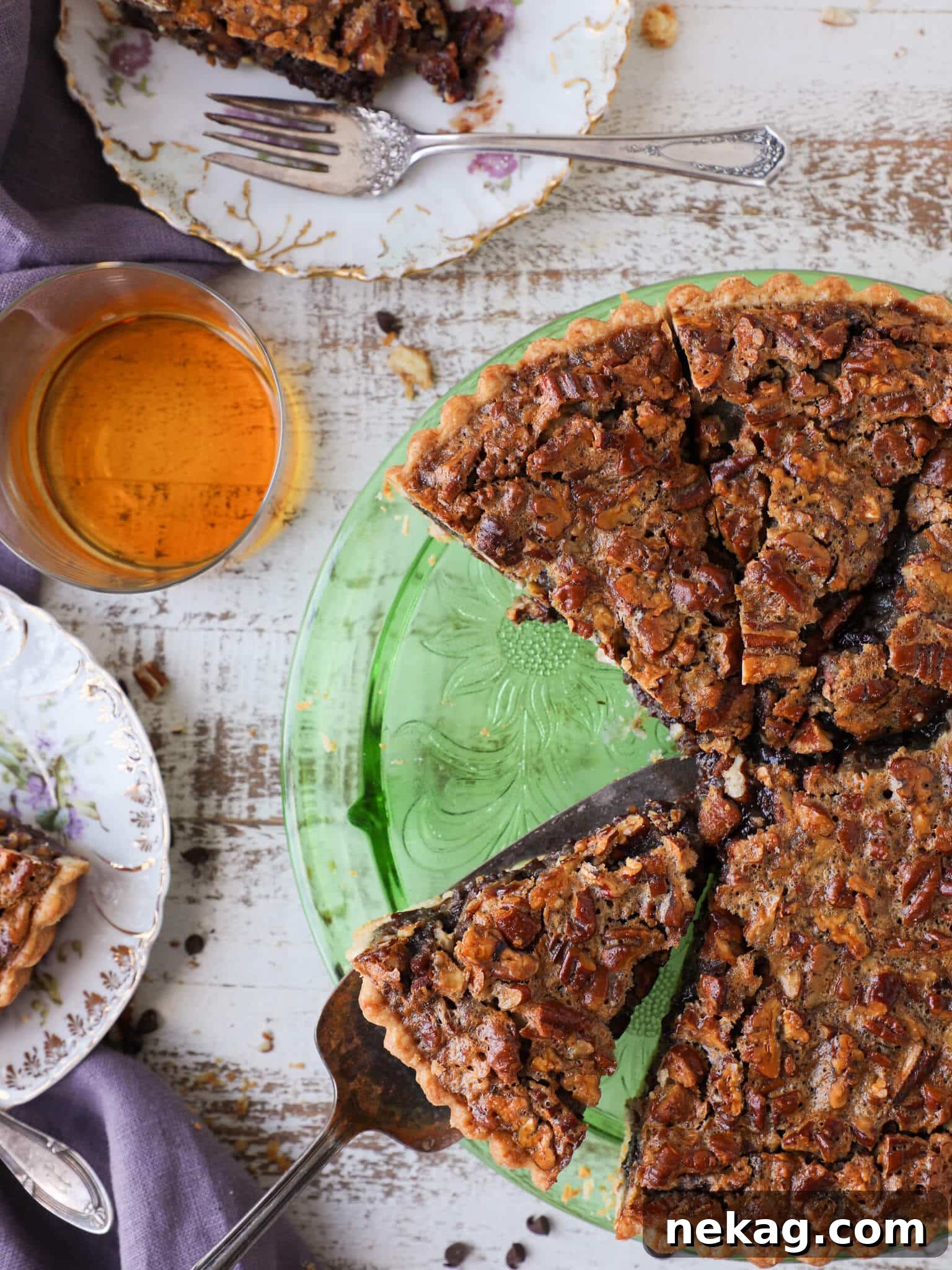 A slice of Bourbon Chocolate Pecan Tart being served on a plate, showcasing its rich filling and pecan topping.