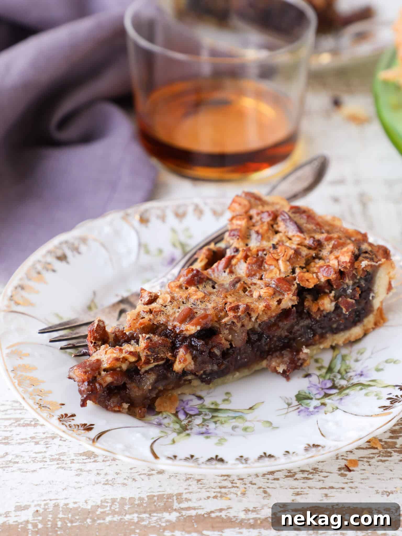 A delectable slice of Bourbon Chocolate Pecan Tart served with a purple napkin, highlighting the rich filling and golden crust.