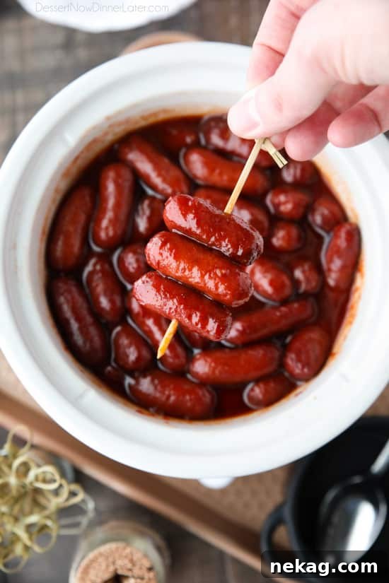 Close-up of three-ingredient Crockpot Little Smokies simmering in a sweet and tangy sauce inside a slow cooker.