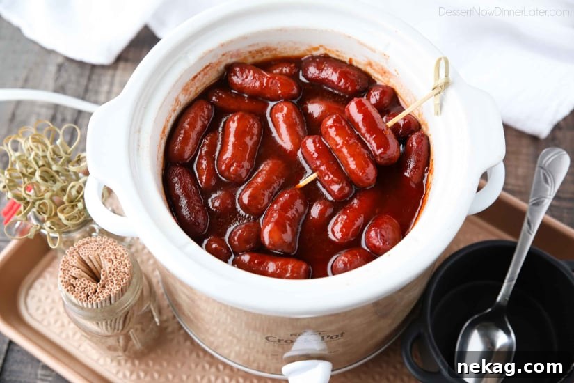 Overhead view of a Crockpot filled with simmering Little Smokies and a rich, sweet, and tangy sauce.