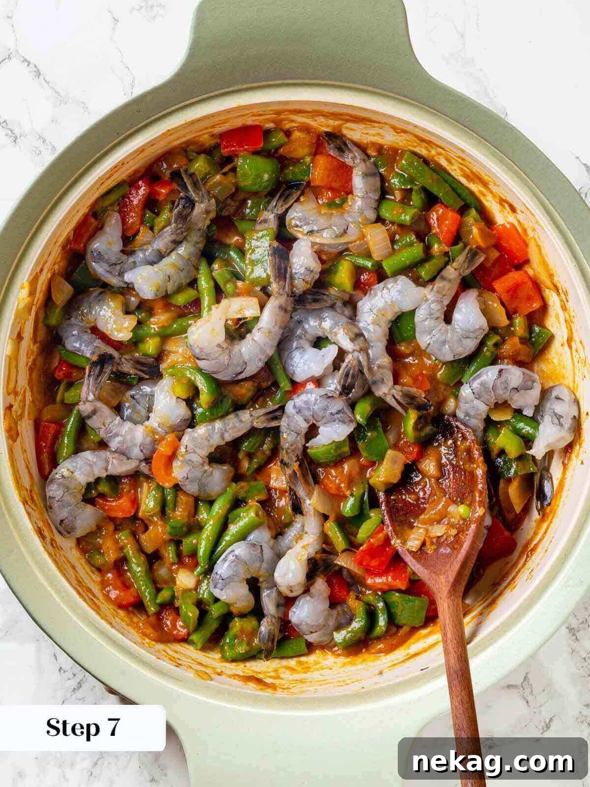 Fresh shrimp being added to the simmering curry mixture in a skillet.