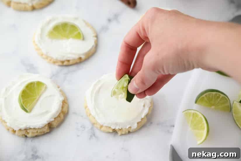 Coconut Lime Sugar Cookies - an easy sugar cookie recipe with a tropical fruit twist. You'll love these moist sugar cookies with a hint of lime, creamy coconut frosting, and a fresh lime wedge to squeeze on top. A Twisted Sugar copycat recipe.