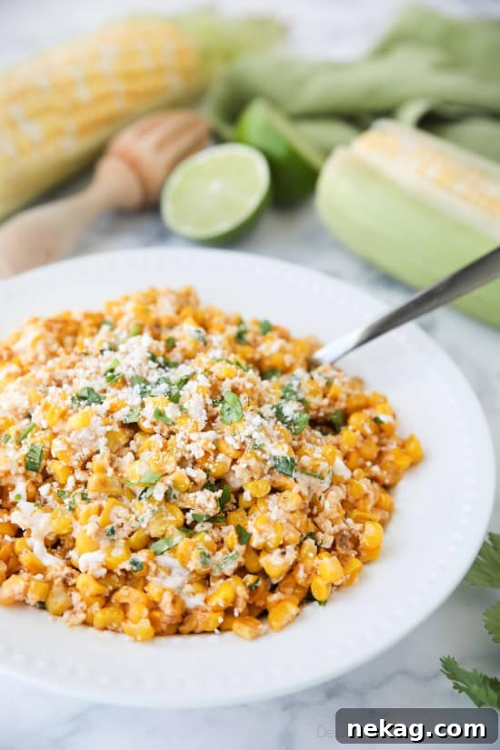 Mexican Street Corn Salad (Esquites) served in a vibrant bowl, garnished with fresh cilantro and a lime wedge, ready to eat.