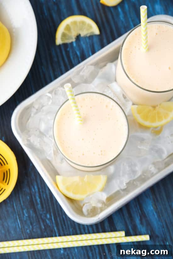 Ingredients for frosted lemonade laid out: fresh lemons, a bowl of granulated sugar, and a carton of vanilla ice cream, ready for blending.