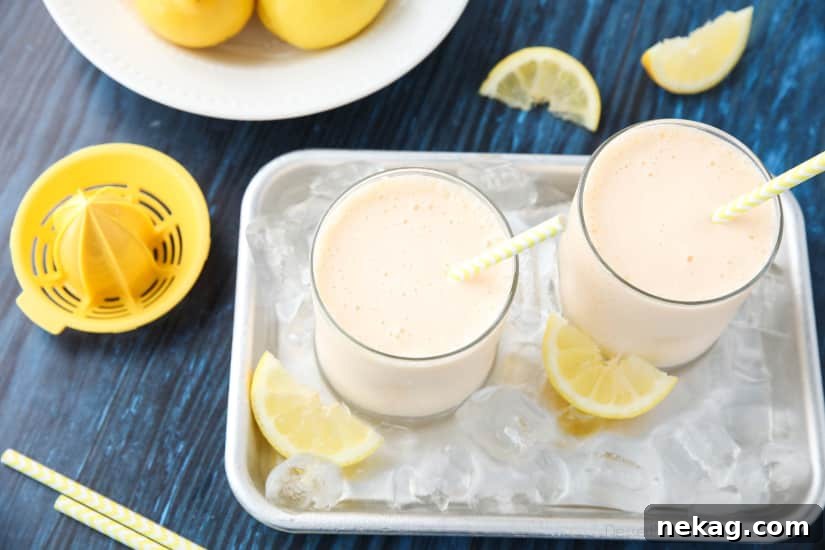 A top-down view of two glasses of frosted lemonade, one with a lemon slice garnish, showcasing the refreshing yellow color and thick texture.
