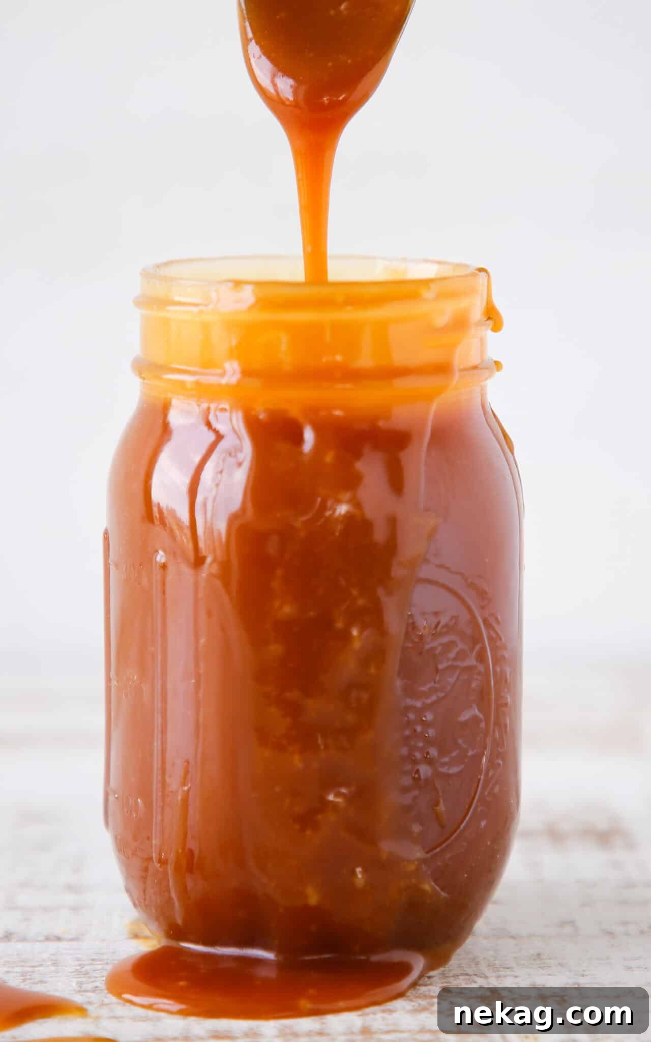 Salted Caramel Indulgence 2 Thick salted caramel sauce pouring from a spoon into a glass jar, ready to be stored or enjoyed.