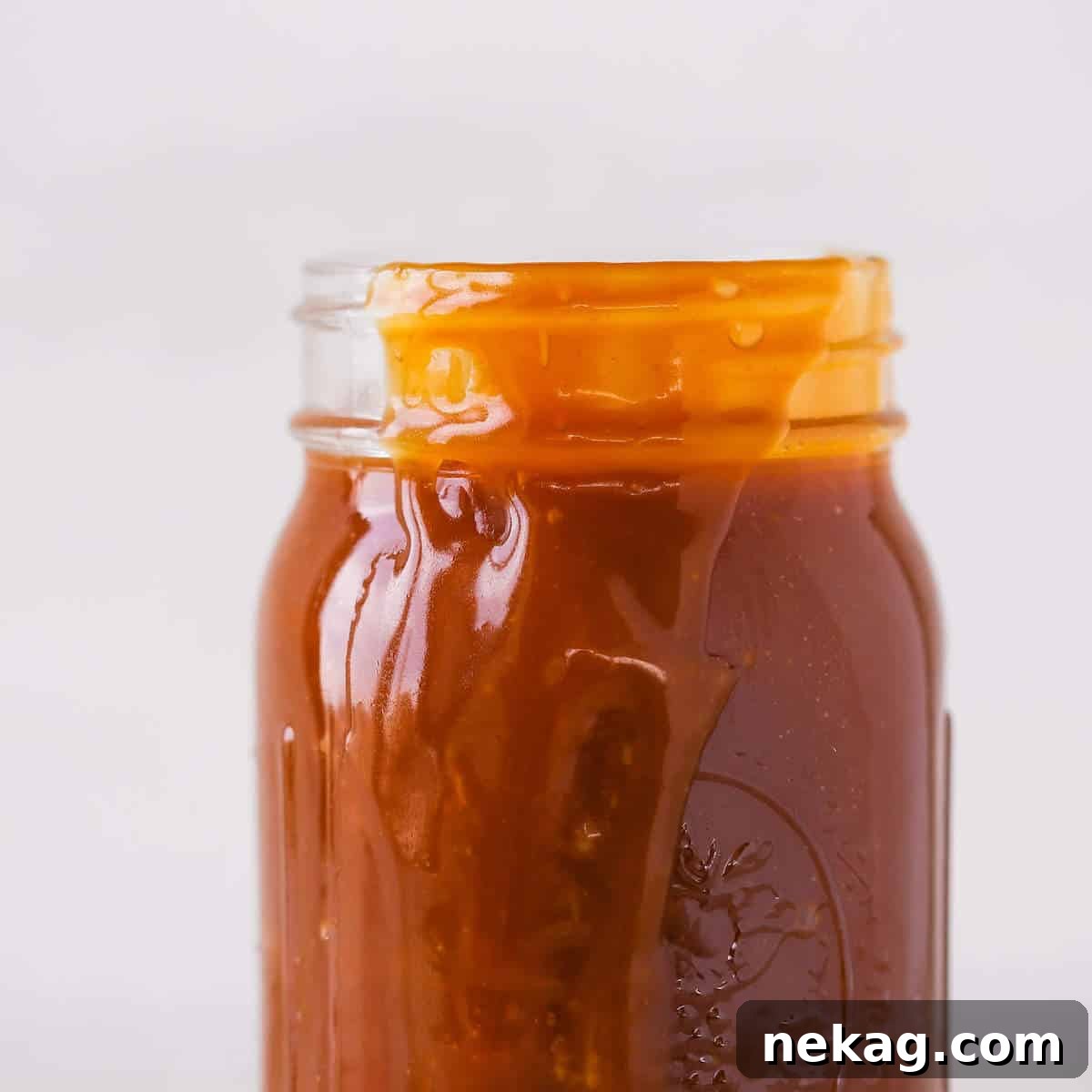 Salted Caramel Indulgence 4 Rich salted caramel sauce gracefully spilling over the side of a glass jar, highlighting its luxurious texture.