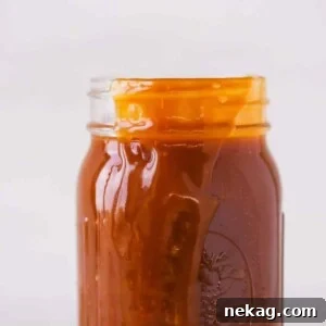 The Best Salted Caramel Sauce spilling over side of a jar, inviting to be enjoyed.