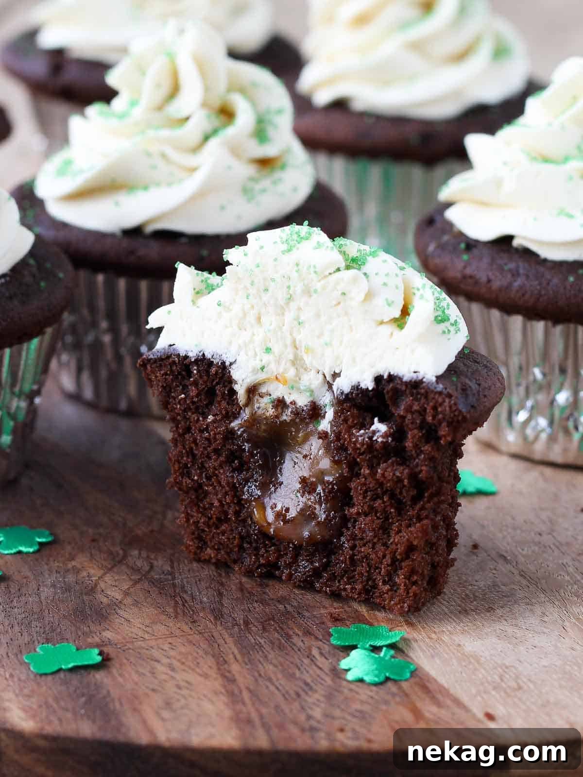A chocolate cupcake cut in half, revealing a luscious salted caramel filling oozing from its core, topped with creamy frosting.
