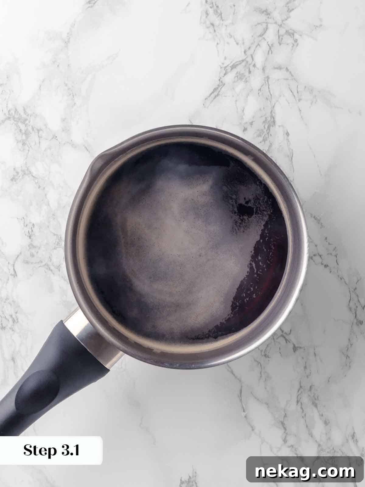 Guinness beer is brought to a bare simmer in a small saucepan, ready to be poured over chocolate ingredients.