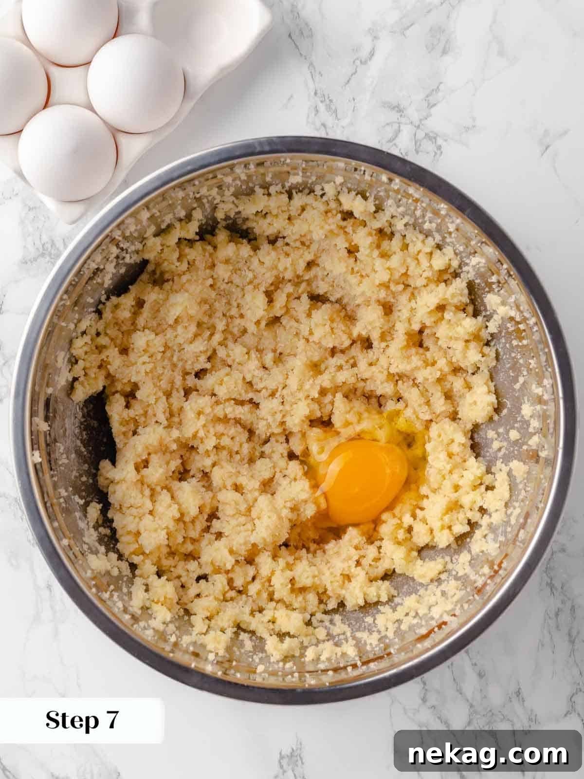 Eggs being beaten into the creamed butter and sugar mixture in a stand mixer bowl, ensuring a smooth texture.