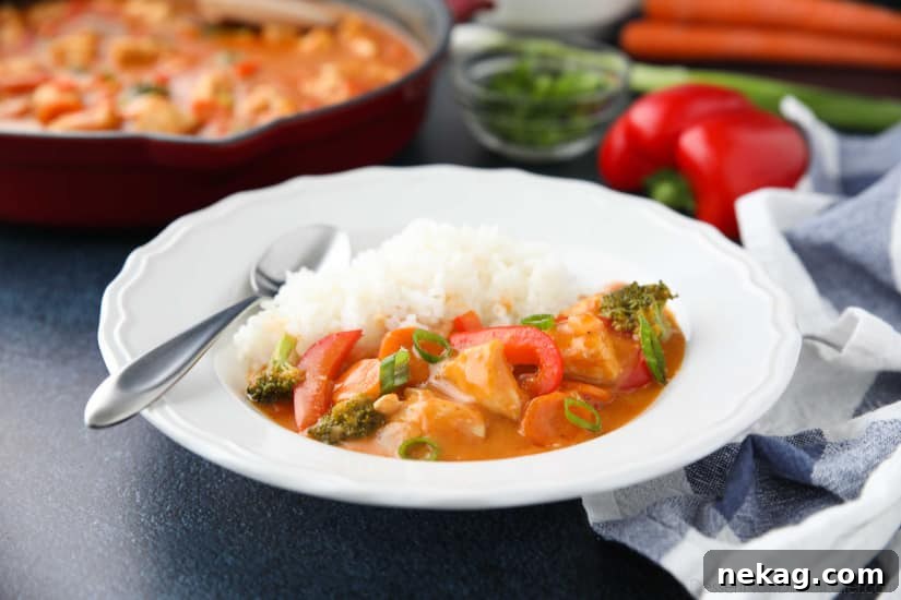Vibrant Thai Red Curry 7 A beautifully plated bowl of Thai Red Curry with chicken and vegetables, served with a side of rice, garnished with fresh cilantro and lime wedges.