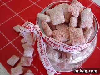 Close-up of Cherry Cheesecake Muddy Buddies showcasing their powdered sugar coating and cherry color.