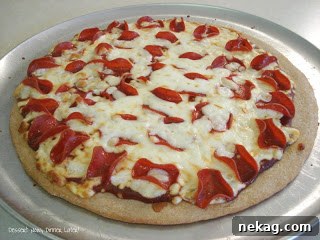 Two pizzas with whole wheat crust, topped and ready for the oven