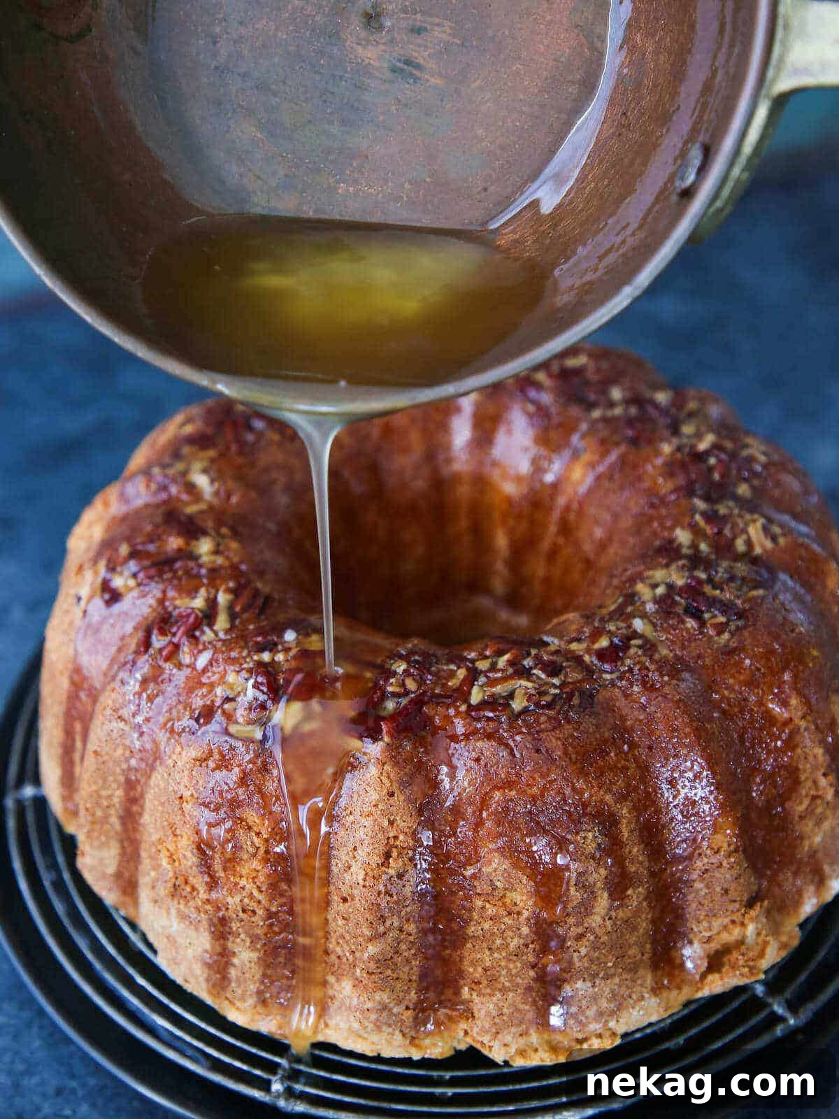 Spirited Bacardi Delight 7 Rum glaze being poured generously over the Bacardi Rum Cake from a copper pot, creating a shimmering finish.