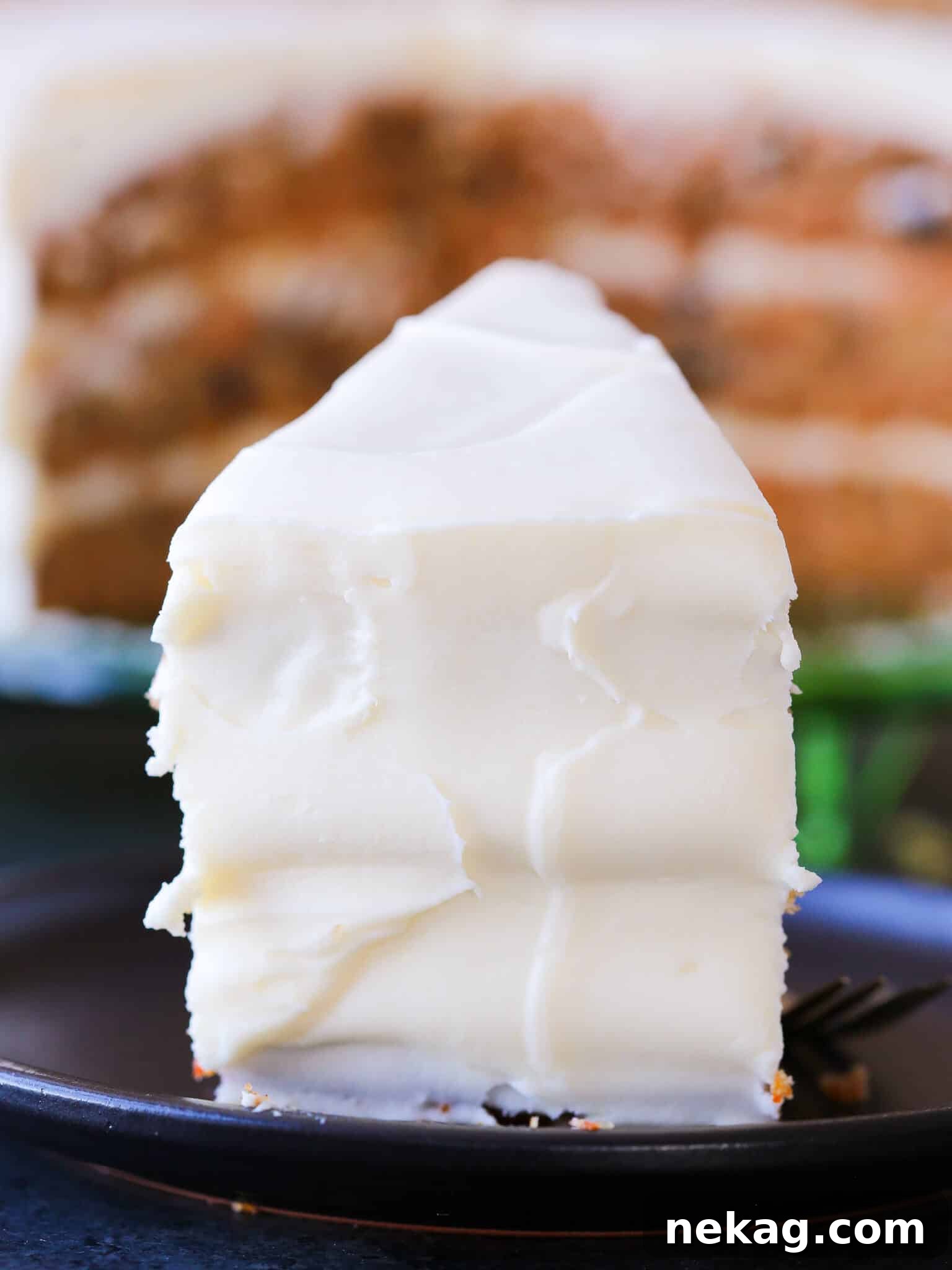 A smooth, frosted slice of carrot cake, highlighting its rich texture and topping.