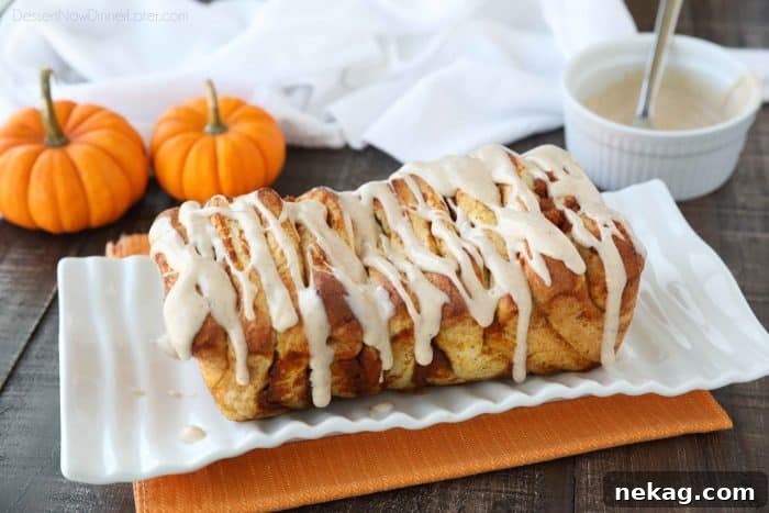 An appetizing whole loaf of Pumpkin Pull Apart Bread, freshly baked to a golden brown perfection, cooling down before the final glazing step.
