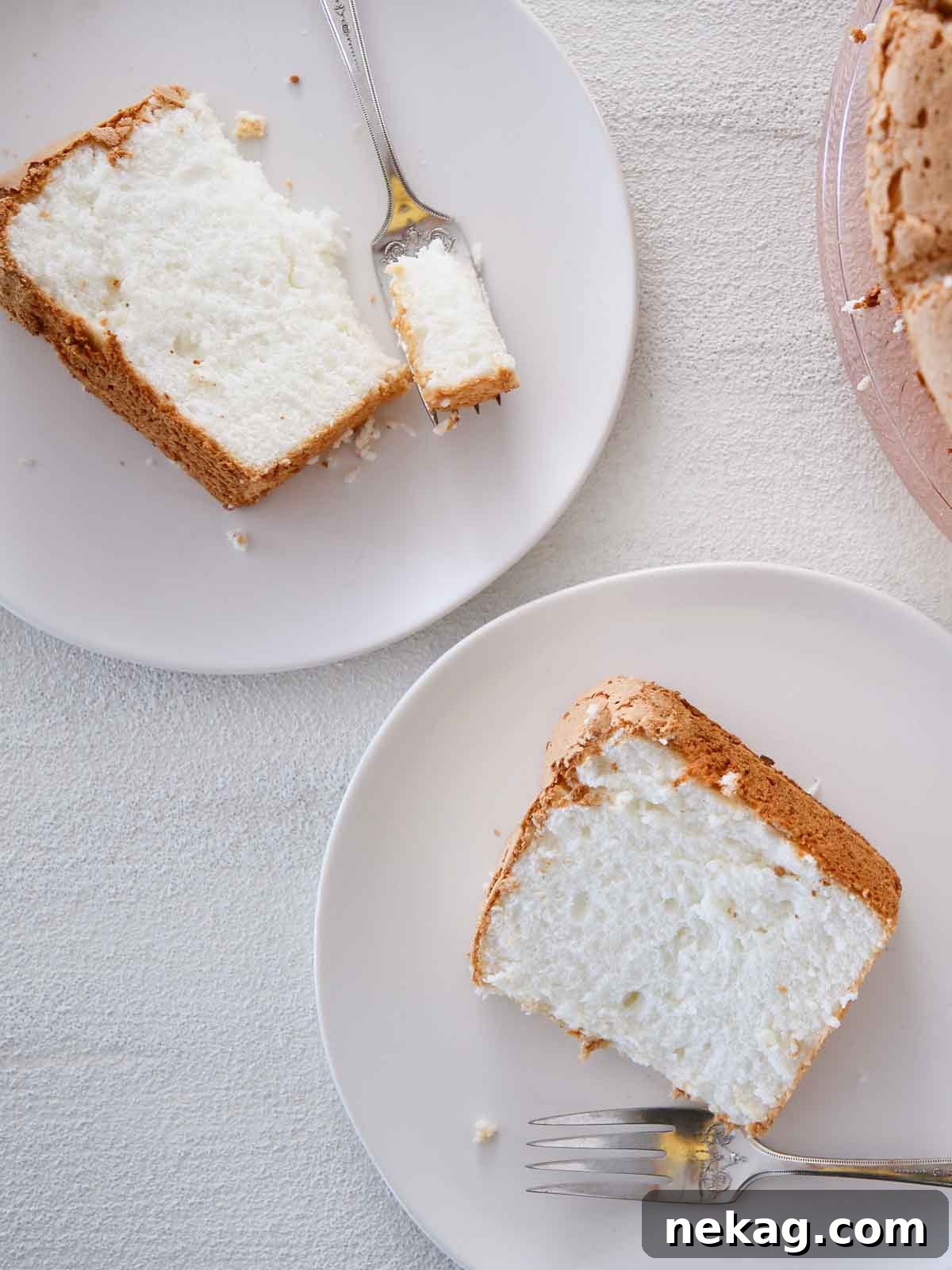 Whisper-Light Delight 2 A beautifully sliced white angel food cake served on white plates, highlighting its airy texture.