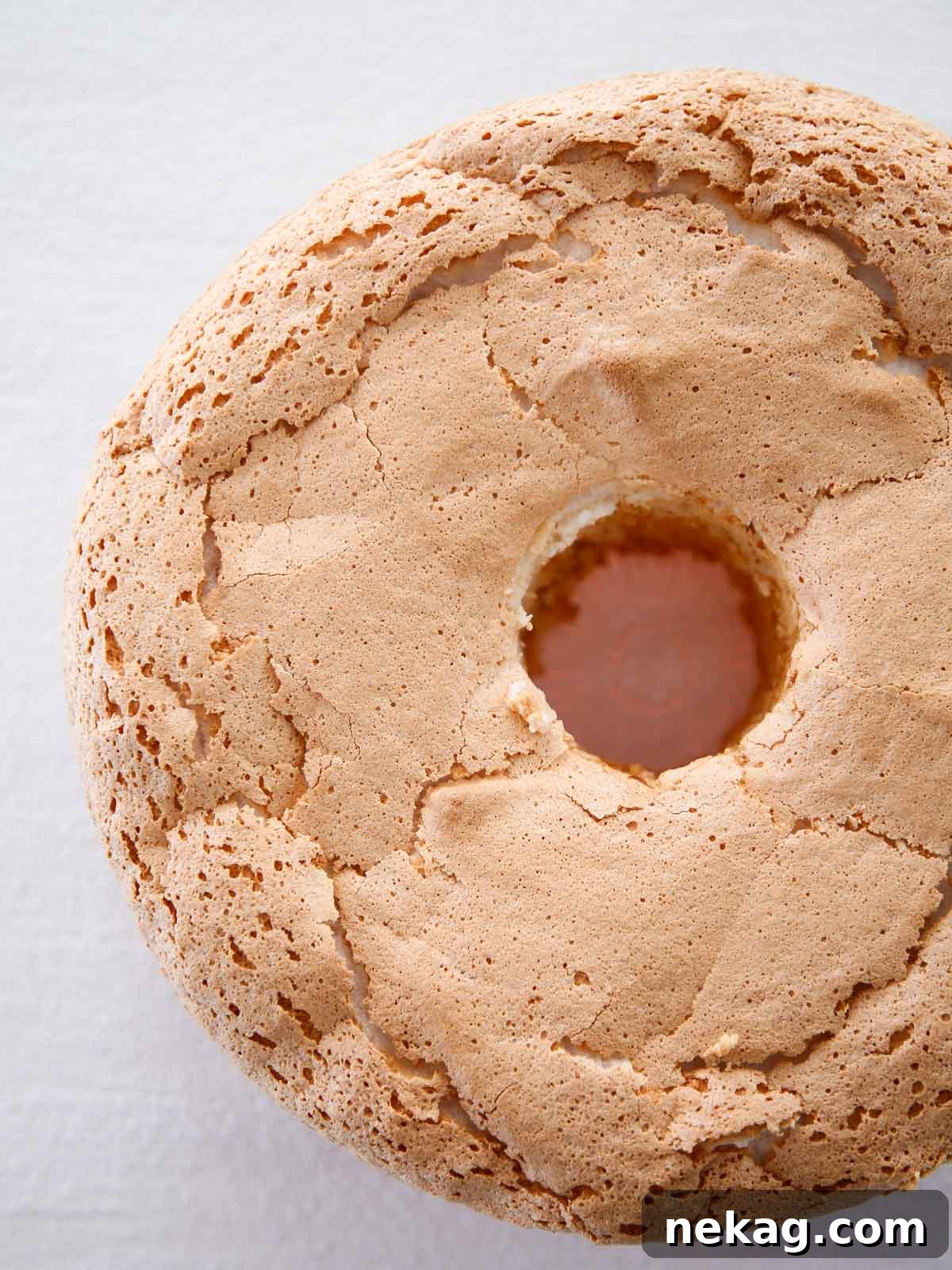 Whisper-Light Delight 4 A perfectly baked, unsliced angel food cake, golden brown on top, ready for cooling.