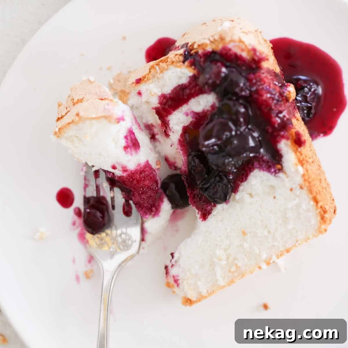 Whisper-Light Delight 5 A delectable slice of angel food cake with a bite taken from a fork, showcasing its soft texture.