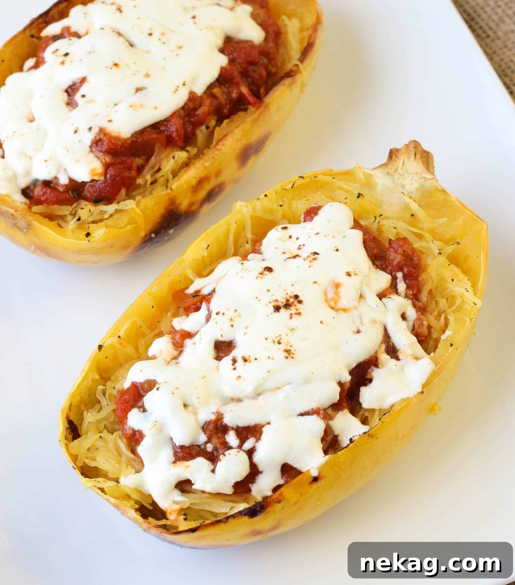 Three servings of Twice Baked Spaghetti Squash with turkey sauce and cheese in a baking dish