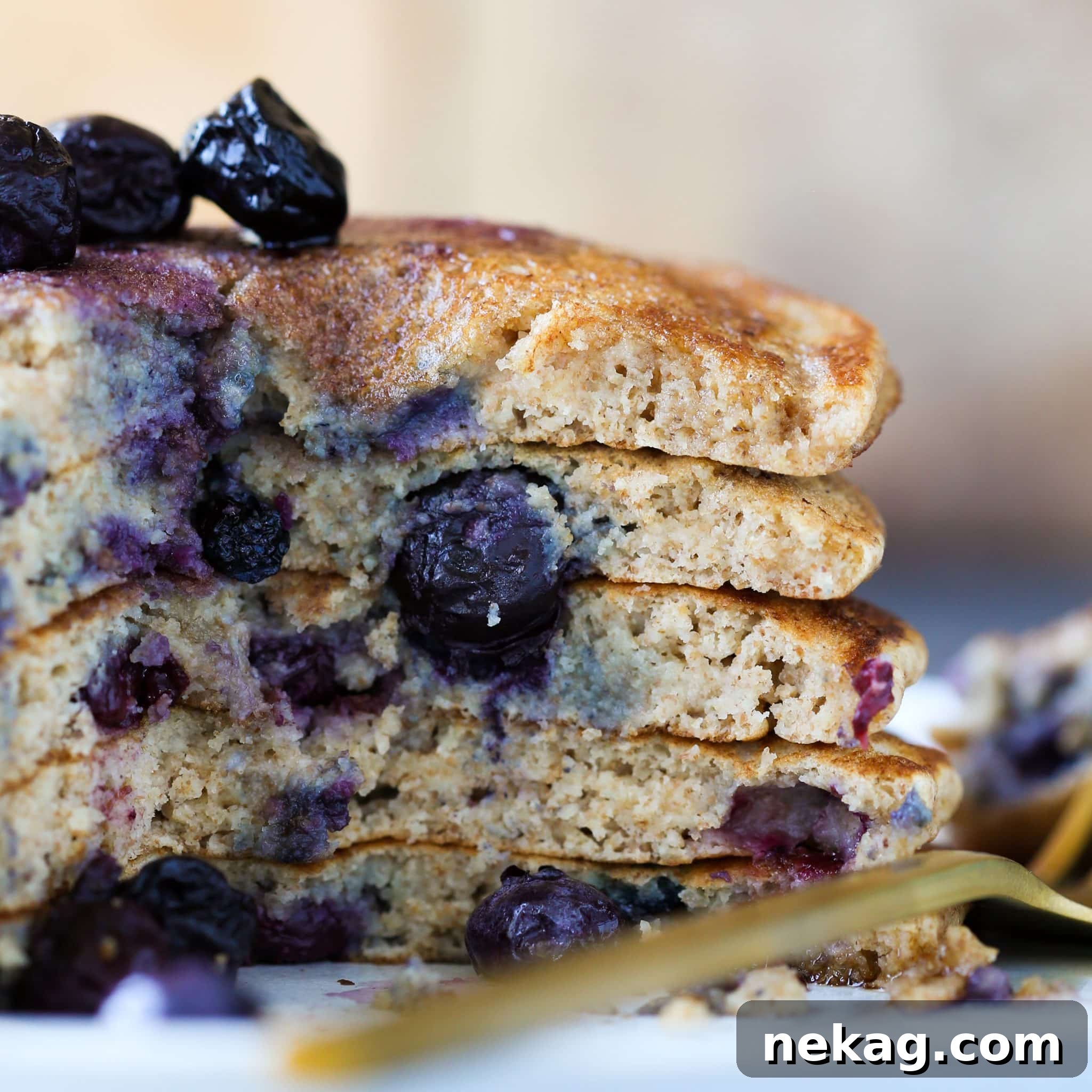 Fluffy Whole Wheat Pancakes stacked high with blueberries and maple syrup