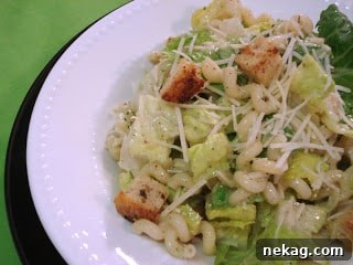 Creamy Caesar Pasta Delight 4 A bowl of Caesar Pasta Salad with dressing and ingredients visible.