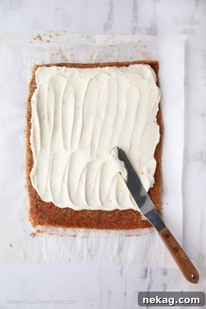 Sweet Swirls: Carrot Cake Roll Recipe 5 Cream cheese frosting being expertly spread over a thin layer of spiced carrot cake, preparing for the roll.