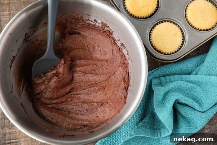 A large bowl filled with creamy, homemade chocolate buttercream frosting, ready to be used.