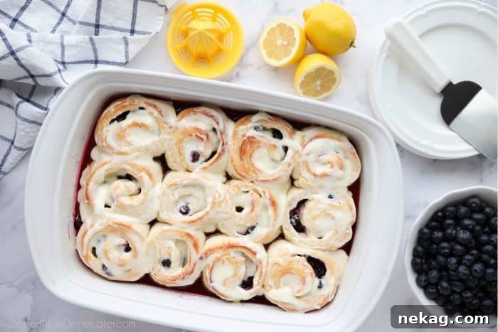 Zesty Lemon Blueberry Buns 5 Freshly baked Lemon Blueberry Sweet Rolls generously covered in a luscious lemon cream cheese frosting, ready to be enjoyed.