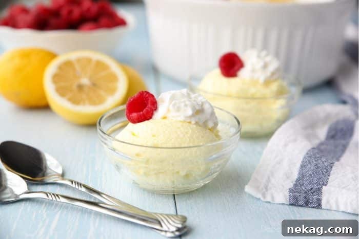 Individual bowls of lemon fluff dessert topped with whipped cream and fresh raspberries.