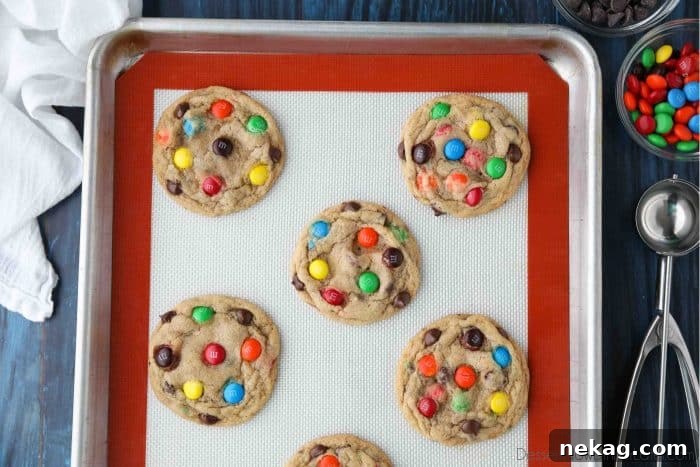 Perfect M and M Cookies Video Guide 5 Freshly baked Chocolate Chip M&M Cookies resting on a sheet tray, steam gently rising.