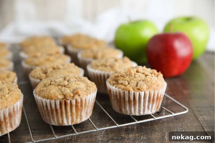 Apple Cinnamon Muffins filled with apples and cinnamon, topped with an irresistible crumb streusel, served on a white platter.