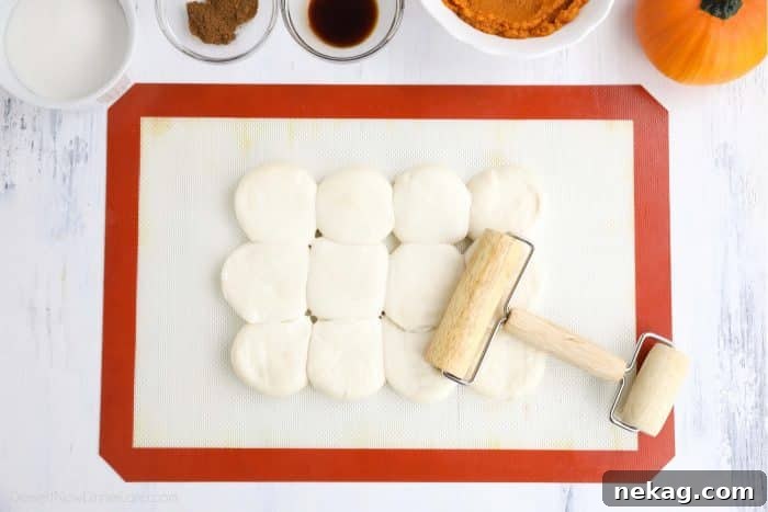 Pumpkin Pie Spiced Cinnamon Rolls 6 Twelve Rhodes dinner rolls being rolled flat and joined together with a mini rolling pin on a floured surface.