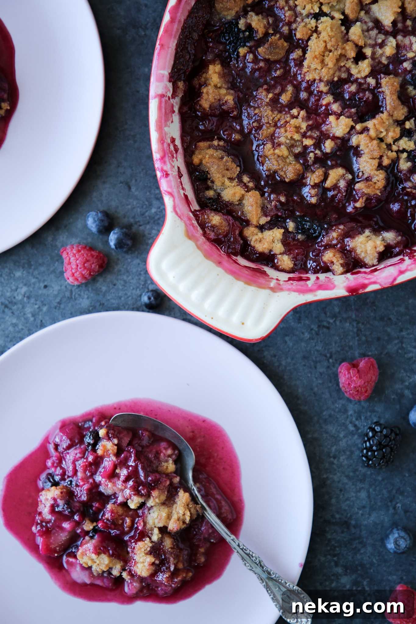 Warm Berry Crumble Bliss 2 A golden-brown mixed berry crumble served in a rustic white baking dish on a vibrant blue background, showcasing its bubbly fruit filling and crumbly topping.